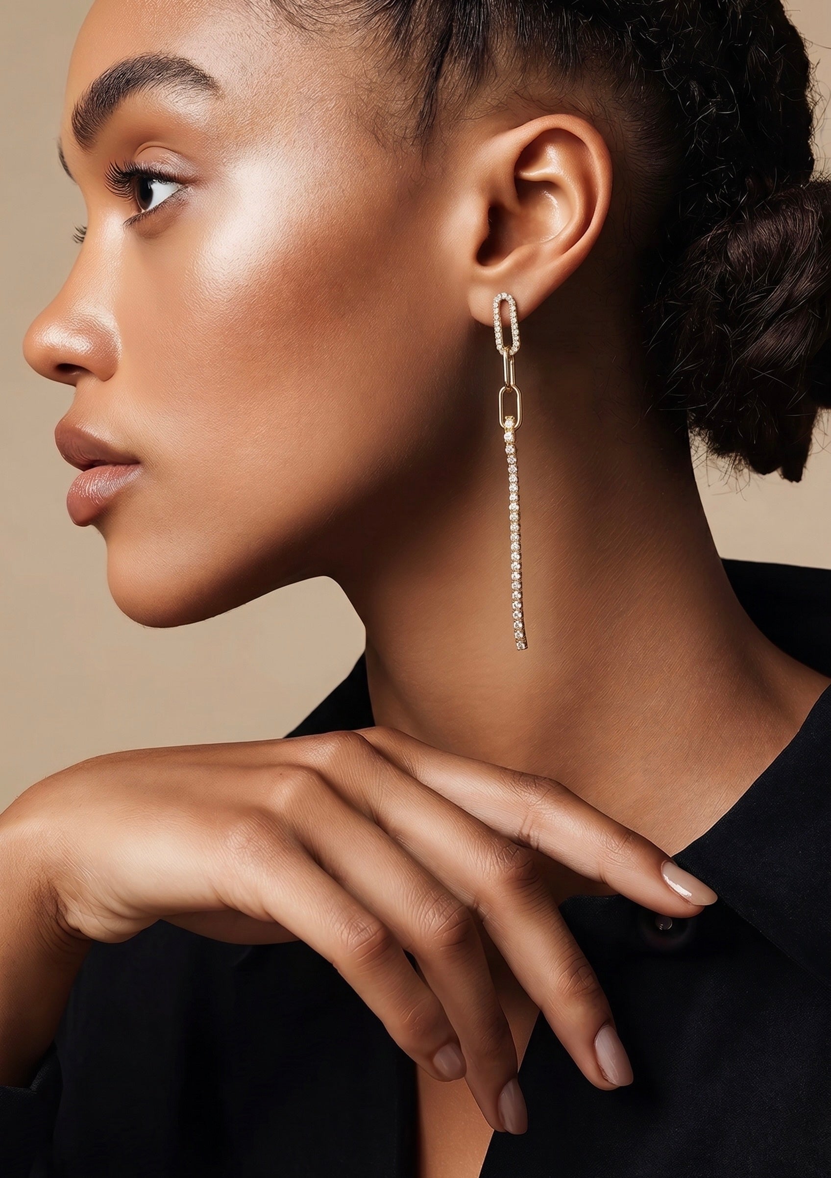 Close-up of a woman wearing a dangling earring with a neutral background